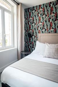 a bedroom with a white bed with a floral wallpaper at La villa 10 HÔTEL SPA in Étretat
