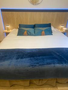 un grande letto con lenzuola e cuscini blu e bianchi di Côté spa a Saint-Victoret