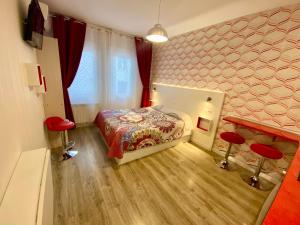 a small bedroom with a bed and two red stools at MuchoMadrid Apartments in Madrid