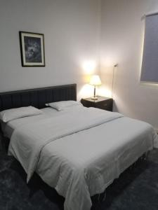 a bedroom with a large white bed with a lamp at شقق الملتقي in Al Nairyah