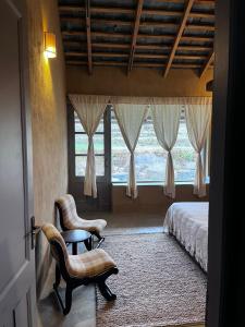 - une chambre avec un lit, deux chaises et une fenêtre dans l'établissement Pala Dharamshala - Mountain Cottage, à Dharamsala