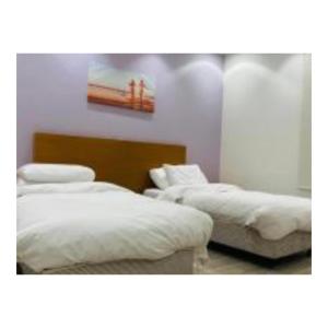 duas camas num quarto com lençóis brancos em Diamond suites em Al Madinah