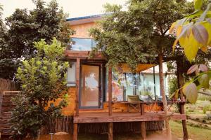 a cabin in the woods with a deck and chairs at Bình An lake view in Buon Ma Thuot