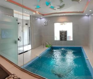 uma casa de banho com uma piscina com uma parede de vidro em فلل الكناري الراقية em Taif