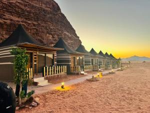 a row of houses in the desert near a mountain at Wadi Rum Desert Tours and Glamping with Hussein in Wadi Rum