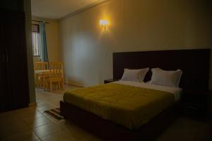1 dormitorio con 1 cama, mesa y sillas en Transit Haven en Entebbe
