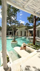 a woman in a hat sitting in a swimming pool at The Yellow Nest Tulum in Tulum