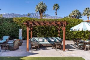 - un kiosque avec des chaises, des tables et un parasol dans l'établissement Villa Del Sol, à Palm Springs