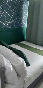 a bed with white sheets and green pillows at Awesome Value, Great Location in Manila