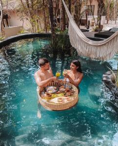 un homme et une femme assis dans une piscine dans l'établissement The Yellow Nest Tulum, à Tulum