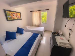 Habitación de hotel con 2 camas y TV en Sweet Caribbean Hotel en San Andrés