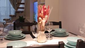 un tavolo con piatti e bicchieri e un vaso con fiori di Desert Rose Apartment- Masdar City a Al Qurayyah