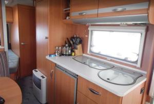 eine Küche mit einem Waschbecken und einem Fenster in einem Wohnwagen in der Unterkunft Wohnwagen mit festem Vorzelt - all incl. in Fehmarn