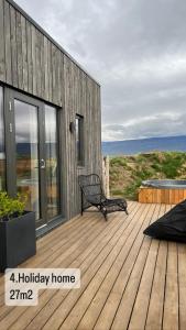 una terraza de madera con un banco en la parte superior de una casa en Armuli en Reynistaður