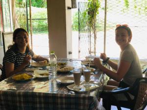 dos mujeres sentadas en una mesa comiendo comida en Sumudu Modern Villa, en Tangalle