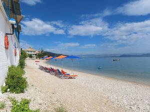 ein Strand mit Stühlen und Sonnenschirmen und dem Wasser in der Unterkunft Blue Sky Studios in Xiropigado