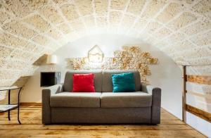 - un canapé avec deux oreillers colorés dans une chambre avec une arche dans l'établissement Casa Melania, à Brindisi