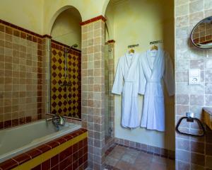 a bathroom with a bath tub and two white robes at Hôtel le Centenaire in Les Eyzies-de-Tayac