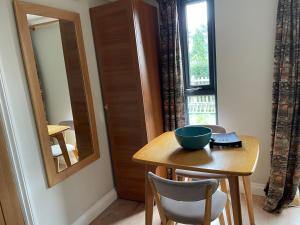 een tafel met een kom er bovenop naast een raam bij Cedar Cabin Holiday Let - Kinver in Stourbridge