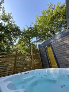 una bañera de hidromasaje en un patio trasero con una valla de madera en Chant des Oiseaux ***, en Royan