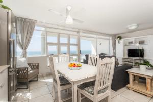 a kitchen and dining room with a table and chairs at Ocean Pearl at Chakas Cove - Beachfront Apartment in Ballito