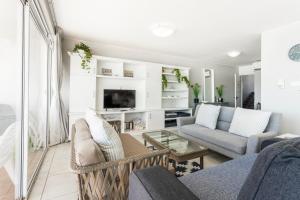 a living room with two couches and a tv at Ocean Pearl at Chakas Cove - Beachfront Apartment in Ballito