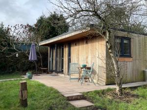 un petit hangar avec une table et des chaises sur une terrasse dans l'établissement Cedar Cabin Holiday Let - Kinver, à Stourbridge