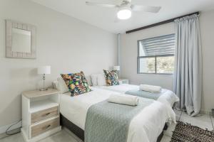 two beds in a white room with a window at Ocean Pearl at Chakas Cove - Beachfront Apartment in Ballito