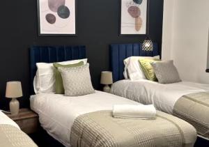 duas camas num quarto com azul e branco em Apartment by DH ApartHotels em Peterborough