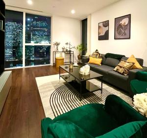 ein Wohnzimmer mit einem Sofa und einem Tisch in der Unterkunft Luxury Modern 2 Bed Flat with Balcony + City View - Canary Wharf City Center in London