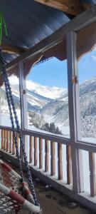 a porch with a rope swing looking out at a snow covered mountain at Devropa Heights in Malāna