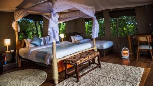 a bedroom with two beds and a canopy bed at Maasai home village in Sekenani
