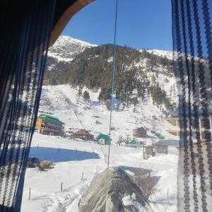 a view of a snow covered mountain from a window at Devropa Heights in Malāna