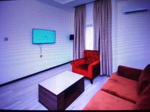 a living room with a red couch and a tv at VILLA TOSCANA asaba in Okpanam