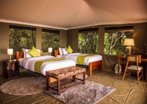 una camera con due letti in una stanza con finestre di Maasai home village a Sekenani