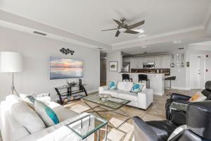 a living room with white furniture and a ceiling fan at The Wave 302 in New Smyrna Beach