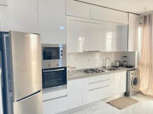 una cocina blanca con armarios y electrodomésticos blancos en Apartamento sublime c/vista top., en Praia