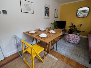 a dining room with a wooden table and yellow chairs at Pass the Keys Charming 2 bed apartment in London