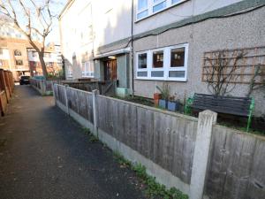 a fence in front of a building with a bench at Pass the Keys Charming 2 bed apartment in London