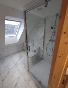 La salle de bains est pourvue d'une douche avec une porte en verre. dans l'établissement Železnohorské Apartmány u Sečskeho zámku, à Seč