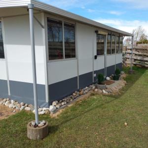 una casa con ventanas y un poste en el césped en Wohnwagen mit festem Vorzelt - all incl. en Fehmarn