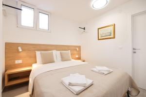 een witte slaapkamer met een groot bed met 2 handdoeken erop bij Vila Barbara in Petrcane