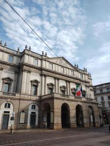 a large building with two flags in front of it at Milano Cordusio in Milan