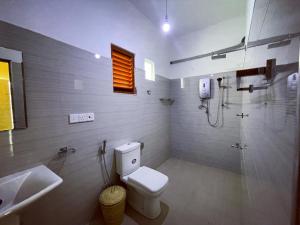 uma casa de banho com um WC, um chuveiro e um lavatório. em Society Ahangama em Ahangama
