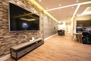 a living room with a large tv on a brick wall at شقة ارضية واسعة Spacious Ground Floor Apartment in Riyadh