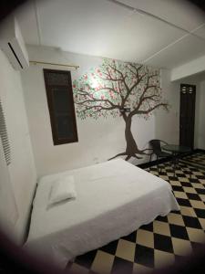 ein Schlafzimmer mit einem an der Wand gemalten Baum in der Unterkunft VEGAN GARDEN HOSTAL in Barranquilla