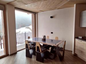 una sala da pranzo con tavolo e una grande finestra di Chalet MAOL Luxury Living a Valdidentro