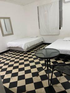 Zimmer mit 2 Betten, einem Tisch und einem Schachbrettboden in der Unterkunft VEGAN GARDEN HOSTAL in Barranquilla