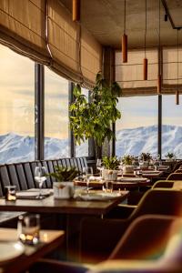 um restaurante com mesas e cadeiras com montanhas ao fundo em Hotel Carpe Diem Gudauri em Gudauri