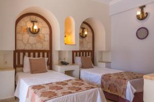 a hotel room with two beds and two tables at Oasis Hotel in Kalkan